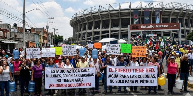 A los habitantes de la colonia Pedregal de Santa Úrsula, junto al estadio Azteca, no les han hecho justicia cuatro Mundiales de Futbol, ni los gobiernos del Partido Revolucionario Institucional, Partido de la Revolución Democrática, ni el Movimiento de Regeneración Nacional. Sus problemas de escasez de agua persisten. IMAGEN: Recreación de protestas en el Estadio Azteca con inteligencia artificial de Gemini